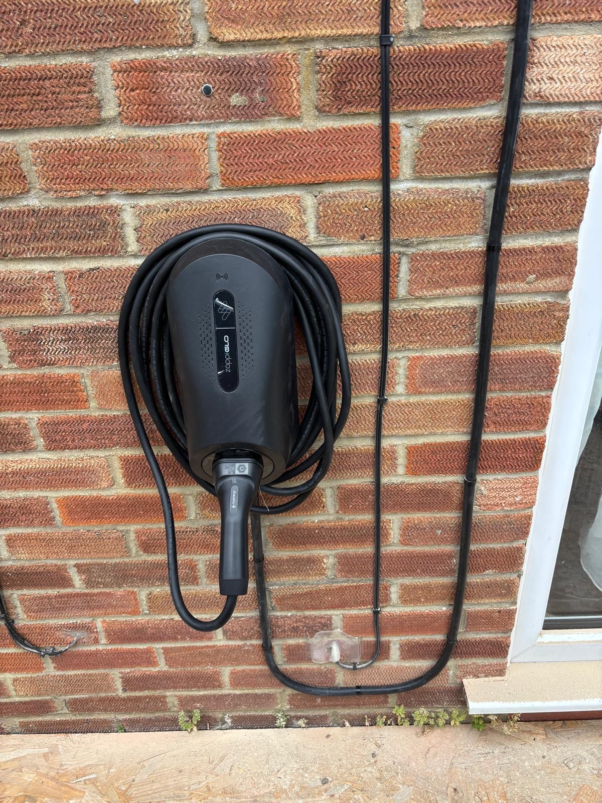 Zappi home EV charger installed on an exterior brick wall by RJ Hill Electrical